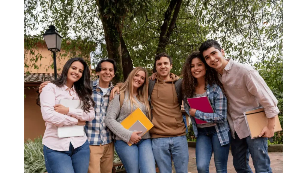 Group of college students smiling and holding notebooks outdoors, representing the camaraderie and team-building experience that escape rooms offer for student organizations at Think in a Box in San Angelo.